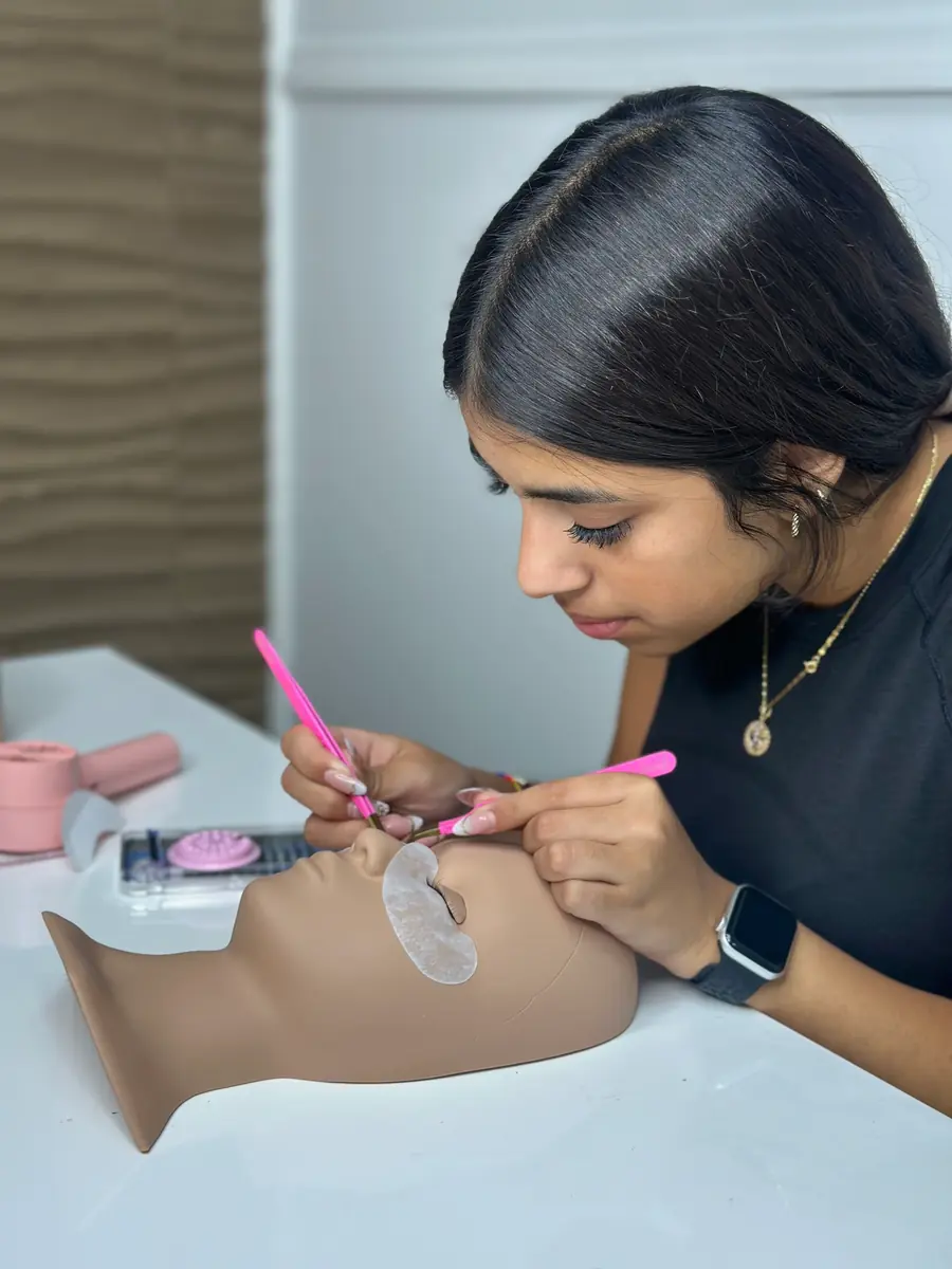 Alumna practicando extensiones de pestañas sobre una cabeza de prácticas